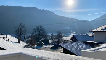 Sonnige Balkonaussicht auf schneebedeckte Berge und die umliegende Landschaft.