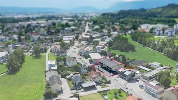 Luftaufnahme der Immobilie in einer städtischen Umgebung mit umliegenden Gebäuden und Bergen im Hintergrund.