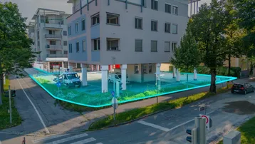 Luftaufnahme eines modernen Gebäudes mit markierten Grundstücksgrenzen und umliegenden Parkplätzen.