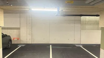 Tiefgarage mit markierten Stellplätzen und sichtbaren Installationen an der Decke.