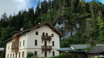 Traditionelles Gebäude mit Holzbalkonen und Blick auf bewaldete Berge.