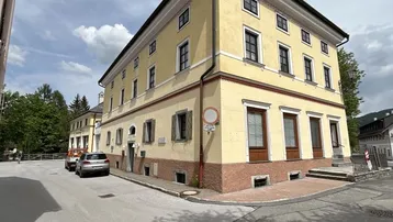 Traditionelles gelbes Eckgebäude mit mehreren Stockwerken und Blick auf die umliegende Straße.
