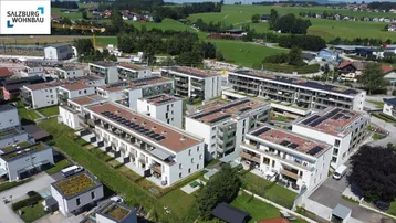 Luftaufnahme einer modernen Wohnanlage mit mehreren Gebäuden und Gründächern in ländlicher Umgebung.