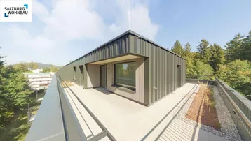 Moderne Dachterrasse mit Fliesenboden, umgeben von Bäumen und mit weitem Blick ins Grüne.