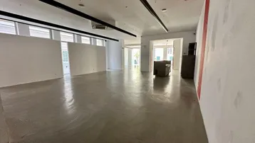 Geräumiger, leerer Geschäftsraum mit hellen Wänden, Betonboden und modernen Deckenleuchten.