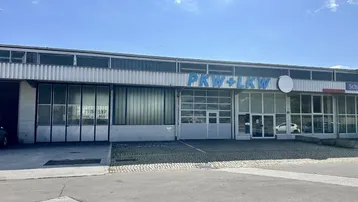Außenansicht eines Gewerbegebäudes mit großen Garagentoren und Fenstern, ideal für Werkstatt oder Service.