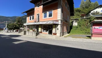 Gebäude mit Geschäften im Erdgeschoss und Wohnungen darüber, an einer Straße gelegen.