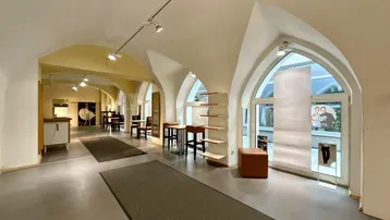 Geräumiger Verkaufsraum mit gewölbten Decken, großen Bogenfenstern und moderner Beleuchtung.