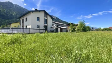 Hausfassade mit weitem Blick auf die umliegende Berglandschaft und grüne Wiesen.