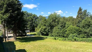 Weitläufiges Grundstück mit grüner Wiese, hohen Bäumen und einem schönen Blick auf die umliegende Natur.