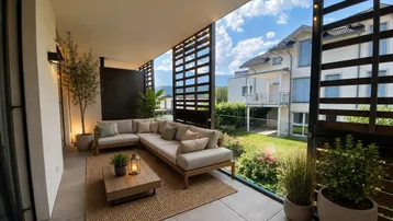 Geräumiger Balkon mit bequemen Loungemöbeln, Holzelementen und Blick ins Grüne.