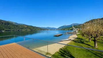 Geräumige Terrasse mit Holzdeck und Glasgeländer, bietet einen atemberaubenden Blick auf den See und die Berge.