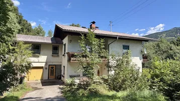 Traditionelles Einfamilienhaus mit Satteldach, Garage und Balkonen in ländlicher Umgebung.
