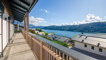 Langer Balkon mit Holzelementen und atemberaubendem Blick auf den See und die umliegenden Berge.