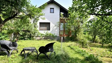 Idyllischer Gartenbereich mit Sitzgelegenheiten und viel Grün rund um das Haus.