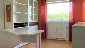 Helles Arbeitszimmer mit großem Fenster, Schreibtisch und praktischen Regalsystemen.