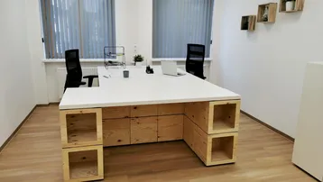 Helles und modernes Büro mit großem Schreibtisch, Holzregalen und viel natürlichem Licht durch große Fenster.