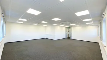 Geräumiges, leeres Büro mit Teppichboden, abgehängter Decke und integrierter Beleuchtung, bereit zur individuellen Gestaltung.