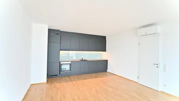 Moderne, offene Küche mit grauen Schränken, integrierten Geräten und hellem Parkettboden.