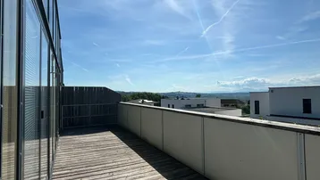 Geräumiger Balkon mit Holzboden und weitem Blick über die umliegende Landschaft.