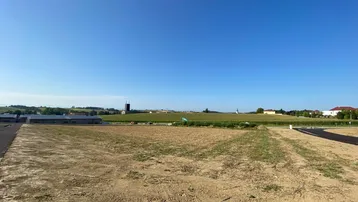 Weitläufiges unbebautes Grundstück mit Blick auf die umliegende Landschaft und ein Gebäude mit Solaranlage.