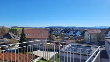 Sonnenterrasse mit Kunstrasen und weitem Blick über die Dächer der Stadt und die Landschaft.