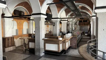 Geräumiger Innenbereich mit gewölbten Ziegeldecken, massiven Säulen und einer langen Holztheke, ideal für Gastronomie.