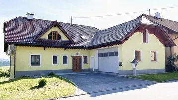 Traditionelles Einfamilienhaus mit gelber Fassade, Satteldach und integrierter Garage.