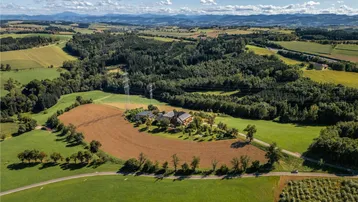 Luftaufnahme eines Anwesens umgeben von Feldern und Wäldern mit Bergblick.