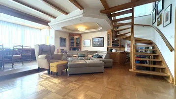 Geräumiger Wohn- und Essbereich mit elegantem Parkettboden, sichtbaren Holzbalken und einer einladenden Treppe.