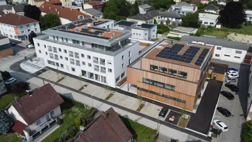 Luftaufnahme von modernen Wohngebäuden mit Photovoltaikanlagen und Parkplätzen.