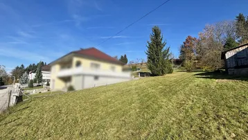 Weitläufige Grünfläche mit leichter Hanglage und Blick auf die umliegende Bebauung.