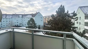 Blick vom Balkon auf die verschneite Umgebung und umliegende Wohngebäude.