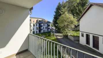 Heller Balkon mit Fliesenboden und Blick auf die umliegenden Gebäude und grüne Landschaft.
