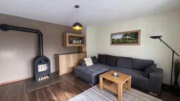 Helles Wohnzimmer mit modernem Holzofen, dunklem Parkettboden und bequemer Eckcouch.