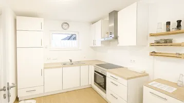 Moderne Einbauküche in Weiß mit Holz-Arbeitsplatten und Fenster für Tageslicht.