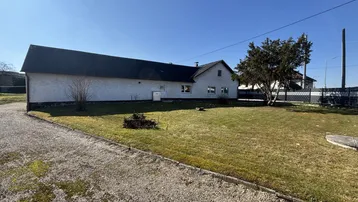 Weitläufiger Gartenbereich mit Rasenfläche und Blick auf das Gebäude unter blauem Himmel.