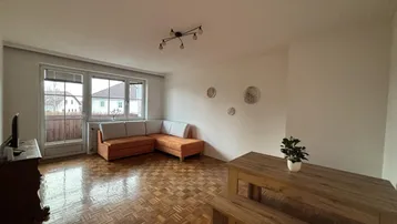 Heller Wohn- und Essbereich mit Parkettboden, gemütlichem Sofa und Holztisch mit Blick ins Grüne.