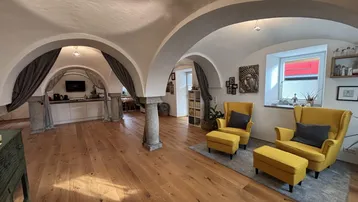 Geräumiger Wohnbereich mit beeindruckenden Gewölbedecken, Holzboden und offener Gestaltung zur Küche.