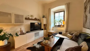 Gemütliches Wohnzimmer mit modernem Mediamöbel, bequemer Couch und einem Fenster mit Blick nach draußen.