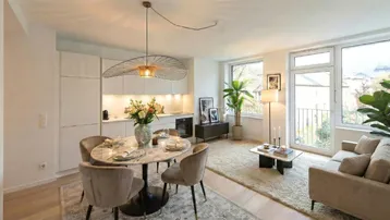 Heller, offener Wohn- und Essbereich mit integrierter Küche, modernem Esstisch und Zugang zum Balkon.