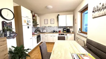 Helle Einbauküche mit Essbereich, weißen Schränken und Parkettboden.