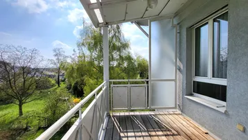 Heller Balkon mit Holzboden und Blick ins Grüne, ideal zum Entspannen im Freien.