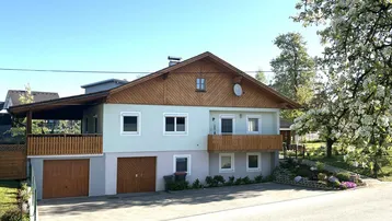 Traditionelles Einfamilienhaus mit Holzbalkonen, Satteldach und integrierter Doppelgarage.