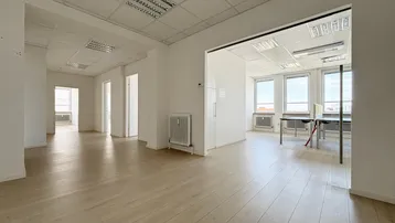 Geräumiges, helles Büro mit hellem Laminatboden und abgehängter Decke, ideal für Großraumbüros.