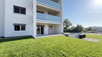 Moderne Wohnanlage mit Balkonen, einer großzügigen Terrasse und gepflegtem Rasenbereich.
