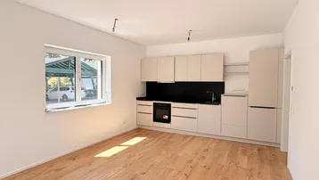 Moderne Einbauküche in hellem Raum mit Holzboden und Blick ins Grüne.