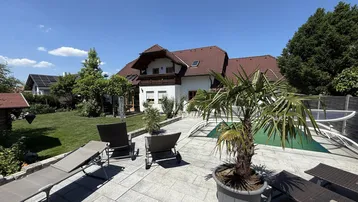 Sonnenverwöhnter Gartenbereich mit Pool, Liegestühlen und gepflegter Rasenfläche hinter dem Haus.