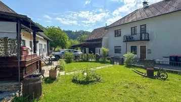Grüner Gartenbereich mit Rasenfläche, Blumenbeeten und Blick auf die umliegende Landschaft.