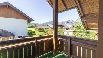 Geräumiger Balkon mit Holzbalken, Kunstrasen und malerischem Bergblick.